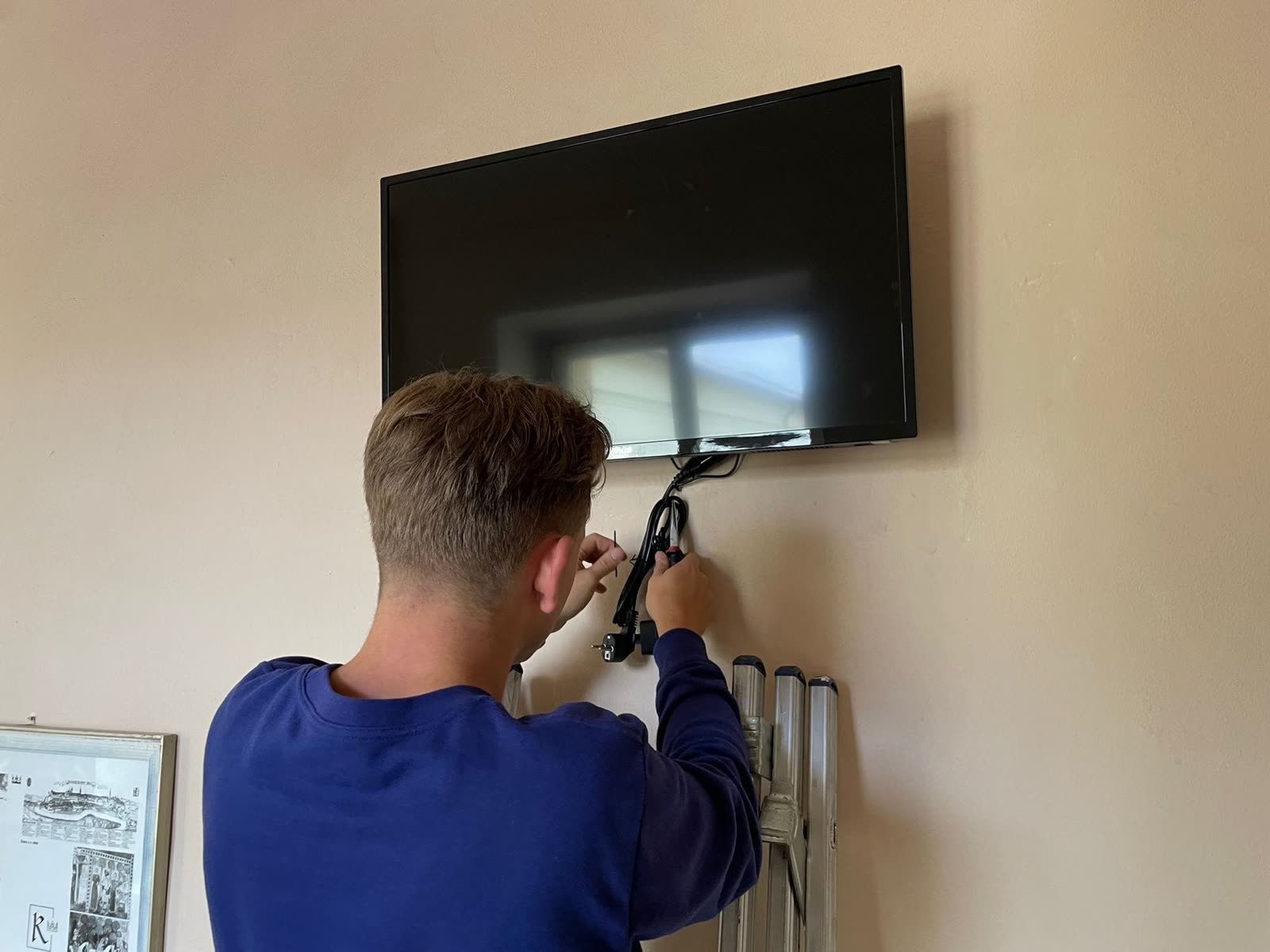 Technician bundling cables under the hung TV